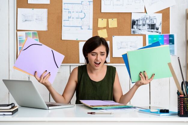 Upset young beautiful businesswoman sitting at workplace